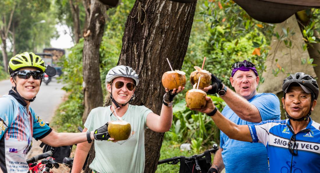 Cyclists enjoying a refreshing coconut roadside in Vietnam | <i>Lachlan Gardiner</i>